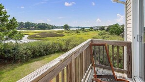 A wooden deck with a view of a river and distant buildings. - Postcards from the Bay (Norfolk)
