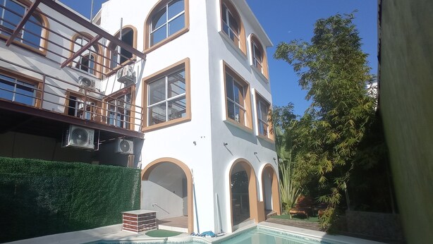 Un edificio de dos pisos con una piscina al frente.