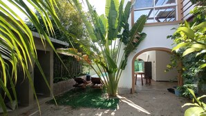 Un patio con césped artificial verde, un banco de madera y una planta en maceta.