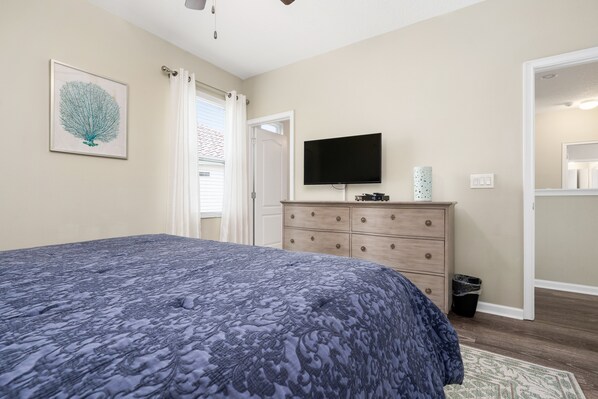 Quarto com cama, penteadeira, televisão e porta.