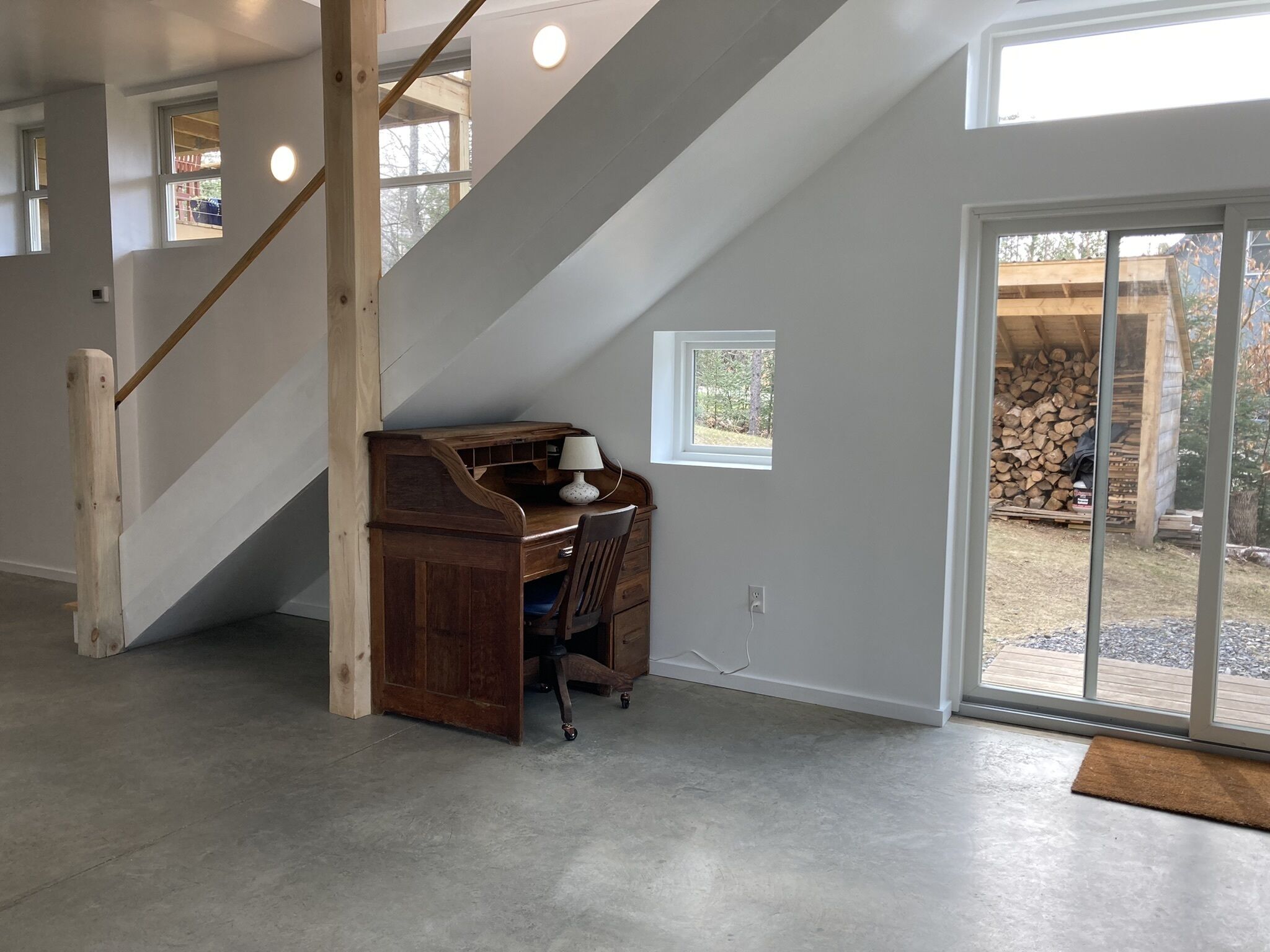 Een modern interieur met een houten bureau, een stoel en een klein raam.