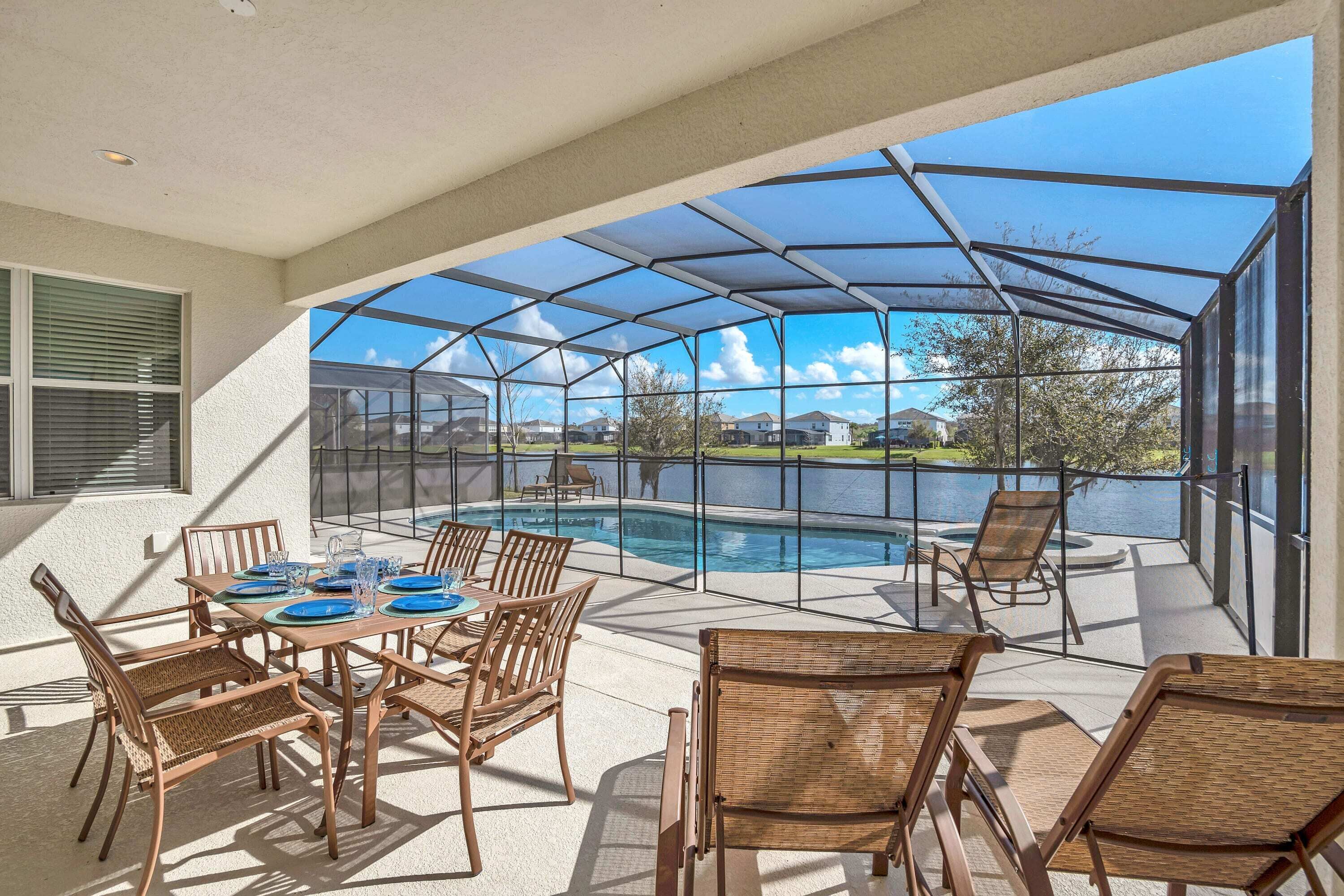 A covered outdoor area with a pool, dining table, and chairs.