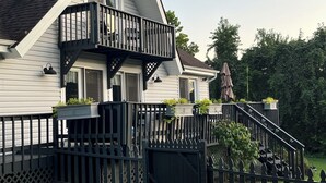 Een tweelaags huis met een balkon, een overdekte veranda en een trap naar de bovenverdieping.