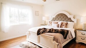 A bedroom with a large bed, a ceiling fan, a window, and a nightstand with a lamp. - Views of Bass Lake, whole house generator, BBQ, Outdoor dining, Mountain Views  (Madera County)