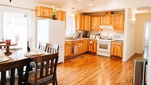 A spacious kitchen with wooden cabinets, a refrigerator, a stove, and a dining area with a table and chairs. - Views of Bass Lake, whole house generator, BBQ, Outdoor dining, Mountain Views  (Madera County)