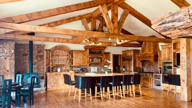 A spacious kitchen with wooden beams, a bar area, and a brick wall.