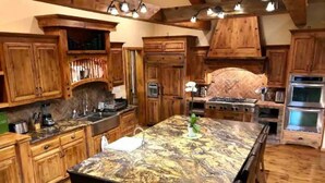 A kitchen with wooden cabinets, a marble island, a stove, and a sink.