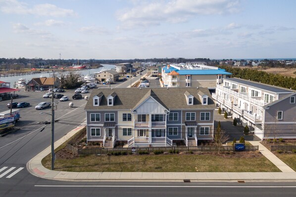 A coastal residential area with multi-story houses, a marina, and a road with parked cars.