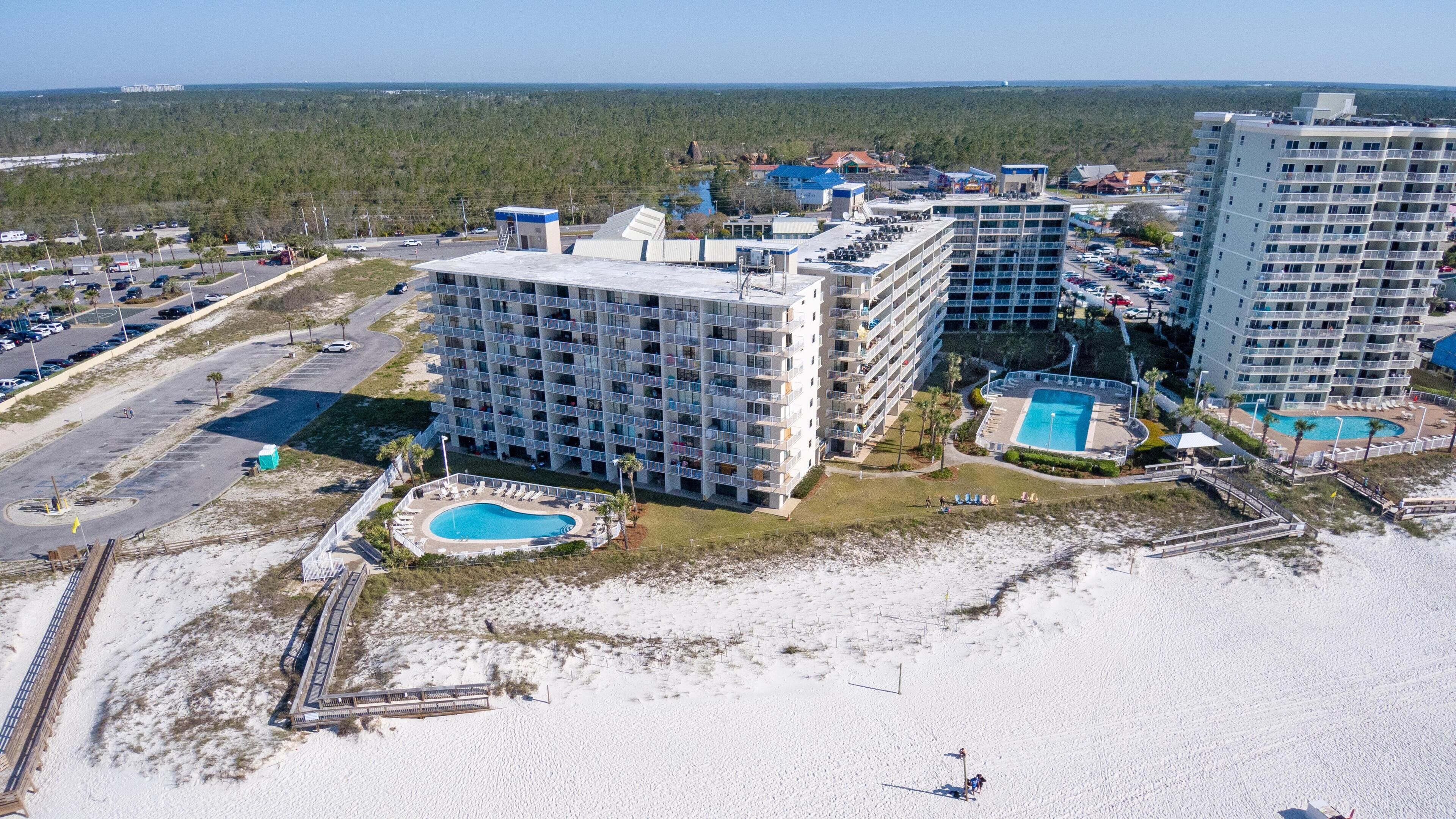 Een hoog hotel met meerdere balkons, een zwembad en een strandgedeelte.