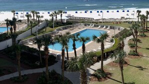 Un complex turístic amb piscina, palmeres i vista a la platja.