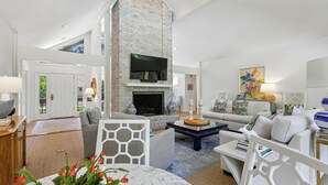 A spacious living room with a fireplace, comfortable seating, and a television.