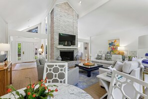 Amplia sala de estar con chimenea, asientos cómodos y televisor.