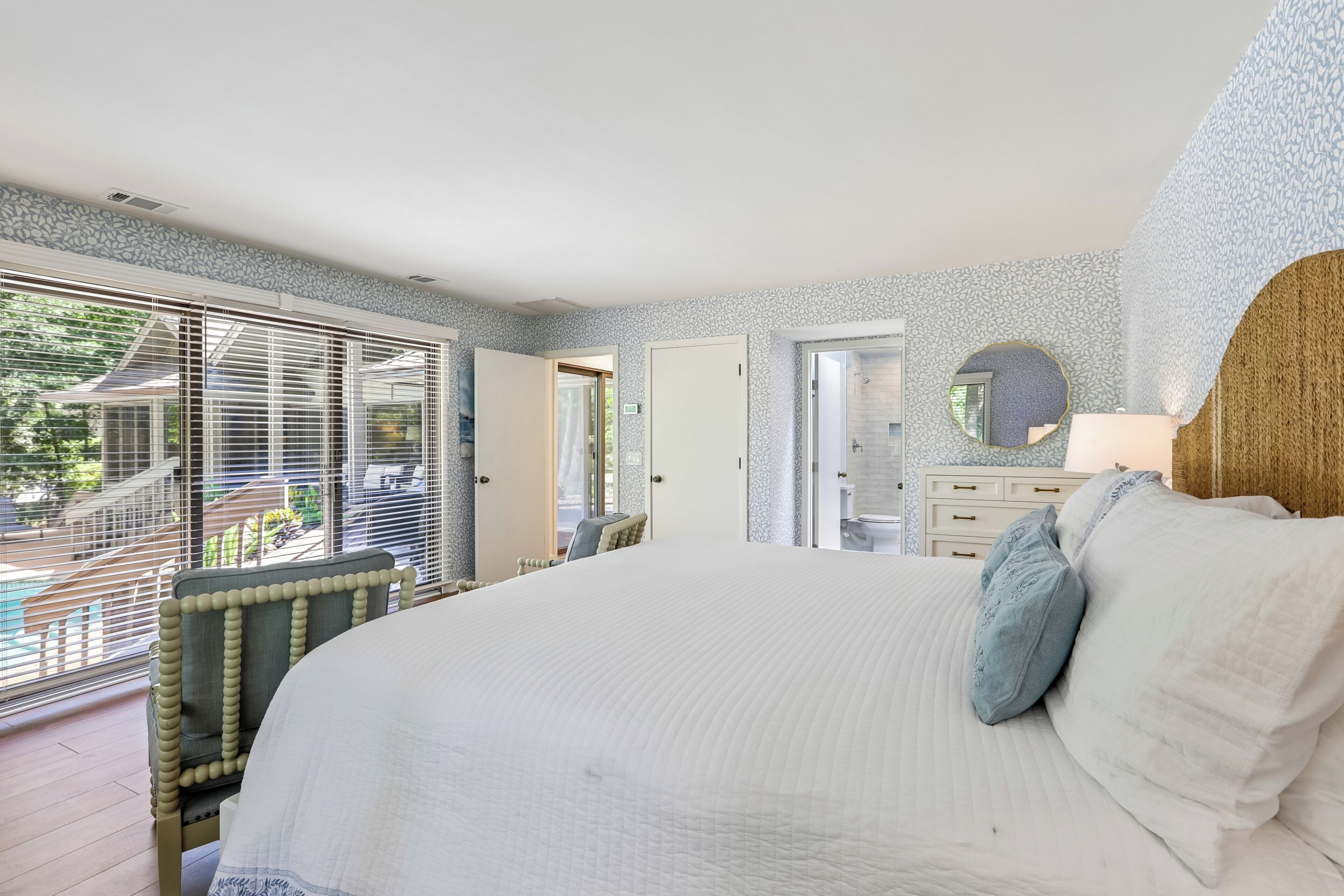 Una camera da letto con un letto grande, una sedia, una cassettiera e vista all'esterno.