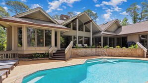 A modern house with a swimming pool, large windows, and a deck.