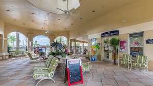 An outdoor patio area with seating, a Coca-Cola sign, and a Hershey's sign. - Luxury, Direct Entry Condo 2BR-2BA - Windsor Hills - Only 2 miles to Disney (Kissimmee)