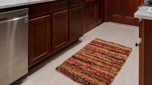 A kitchen with wooden cabinets, a stainless steel dishwasher, and a colorful rug on the floor. - Craftsman Charmer | Easy Access to City & Airport (Pittsburgh)