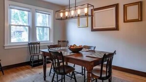 A dining area with a wooden table, six chairs, a chandelier, and a rug. - Craftsman Charmer | Easy Access to City & Airport (Pittsburgh)