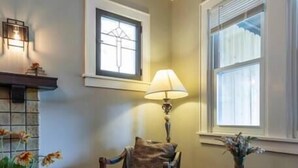 A cozy living room with a fireplace, a comfortable sofa, a wooden coffee table, and a lamp. - Craftsman Charmer | Easy Access to City & Airport (Pittsburgh)