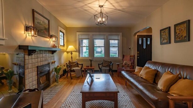 A cozy living room with a fireplace, leather sofa, wooden coffee table, and a patterned rug. - Craftsman Charmer | Easy Access to City & Airport (Pittsburgh)