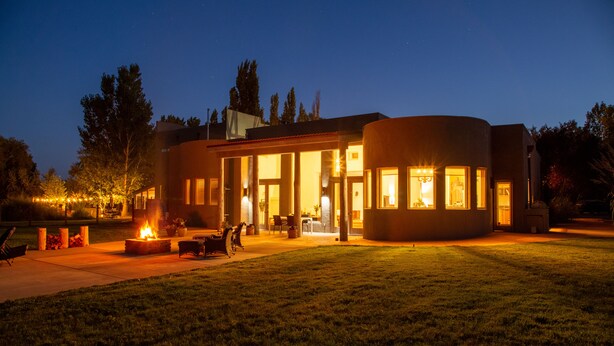 Une maison moderne dotée d’un patio circulaire, d’un espace salon extérieur et d’un foyer.