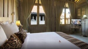 Ein Hotelzimmer mit einem großen Bett, Vorhängen, einem Fernseher und einem Fenster mit Blick nach außen.