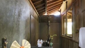 Ein Badezimmer mit Holzboden, einer Badewanne, einem Waschbecken mit Pflegeprodukten und einem Spiegel.
