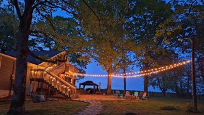 A building with a staircase and outdoor seating area, surrounded by trees and string lights. - Escape to the Country Penthouse (Dickson)
