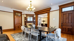 A dining area with a long table, white chairs, and a chandelier. - Heritage Location in Heart of Revelstoke (Revelstoke)