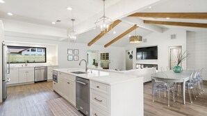 A modern kitchen with white cabinetry, stainless steel appliances, and a large island.