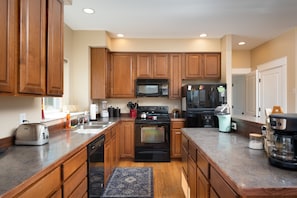 A kitchen with wooden cabinets, a microwave, a refrigerator, a toaster, and a coffee maker. - Three Suites Lodge, Full Private Bathrooms! (Bozeman)