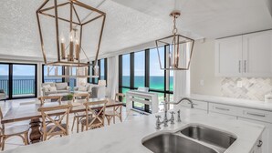 Uma cozinha moderna com uma ilha grande, pia de aço inoxidável e iluminação pendente.