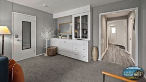 Un intérieur moderne avec un tapis gris, des meubles blancs, un panier en osier et un grand vase.