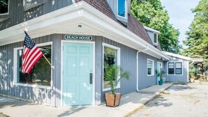 Una casa de dos pisos con una puerta azul claro y un letrero que dice 'Beach House'.