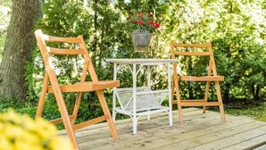 Eine Holzterrasse mit zwei Stühlen und einem kleinen Tisch mit einem weißen Korb.