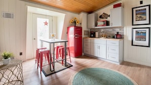 A compact kitchen with white cabinets, a red refrigerator, and a dining area with red stools. - Geneva Beach House Como Suite Walk to Lake Shore Path Near Downtown (Lake Geneva)