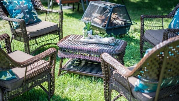 Wicker furniture with cushions, a small table with a pineapple, and a glass enclosure with logs. - Geneva Beach House Como Suite Walk to Lake Shore Path Near Downtown (Lake Geneva)