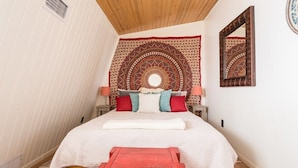 A bedroom with a bed, a red bench, a tapestry, and a mirror on the wall. - Geneva Beach House Como Suite Walk to Lake Shore Path Near Downtown (Lake Geneva)