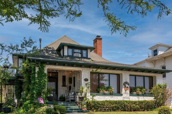 A two-story house with a gabled roof, a chimney, and a covered front porch with steps.