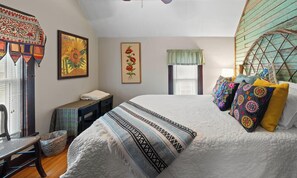 A bedroom with a large bed, a chair, a small table, and a window with a view.
