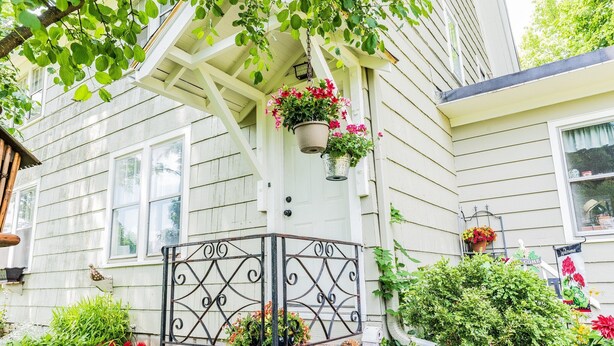A house with a porch, potted plants, and a birdhouse.