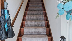 A staircase with wooden steps and carpeted risers, leading to a door with a key lock and a doorbell.