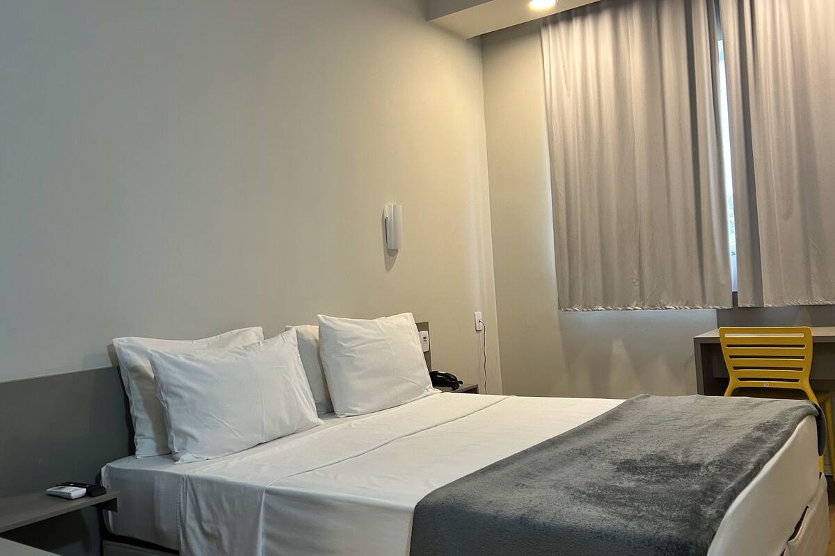 A hotel room with a bed, a desk, and a chair.