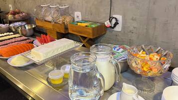 A buffet with various food items and beverages, including sliced meats, fruits, and dairy products.
