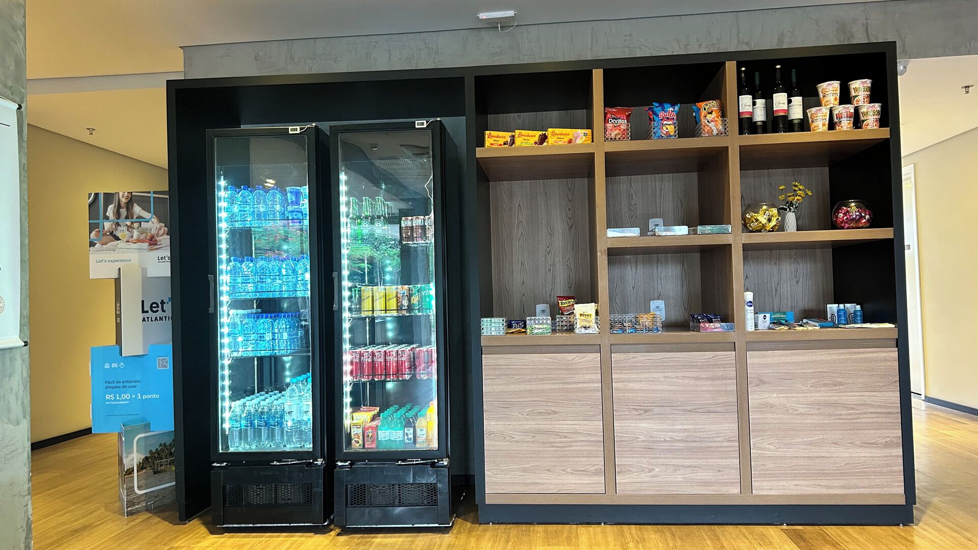 Two beverage vending machines and a shelf stocked with snacks and beverages.
