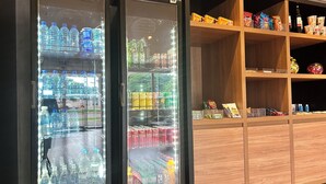 Máquina expendedora con diferentes bebidas y aperitivos, incluyendo agua, cerveza y alimentos envasados.