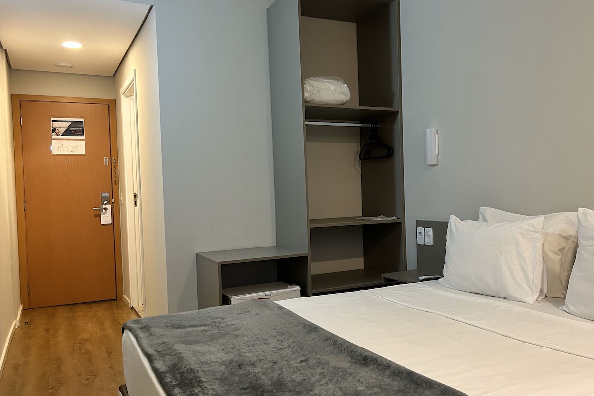 A hotel room with a bed, a wardrobe, and a desk.