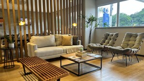 Una sala de estar moderna con sofá, sillones, una mesa de centro y un banco de madera.