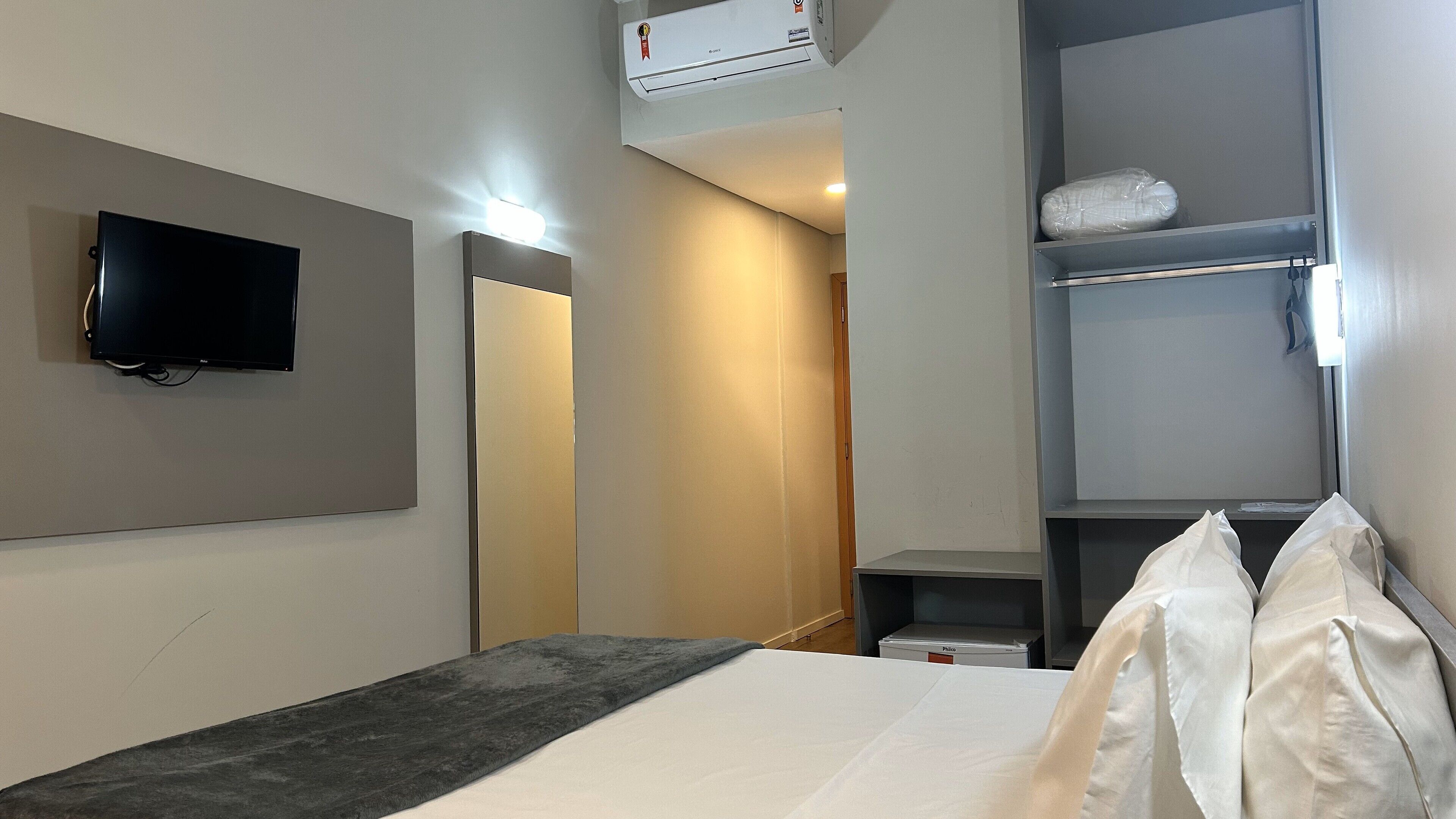 Ein Hotelzimmer mit einem Bett, einem flachbildfernseher an der Wand, einem Kleiderschrank und einer Decken-Klimaanlage.