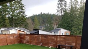 A backyard with artificial grass, a wooden fence, and a bench. - Bachelor's Green Oasis: With Putting Green (Langford)