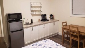 A compact kitchenette with a microwave, refrigerator, coffee maker, and a wine rack. - Bachelor's Green Oasis: With Putting Green (Langford)